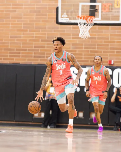 Drew League players in coral and turquoise uniforms advancing up court during Season 53